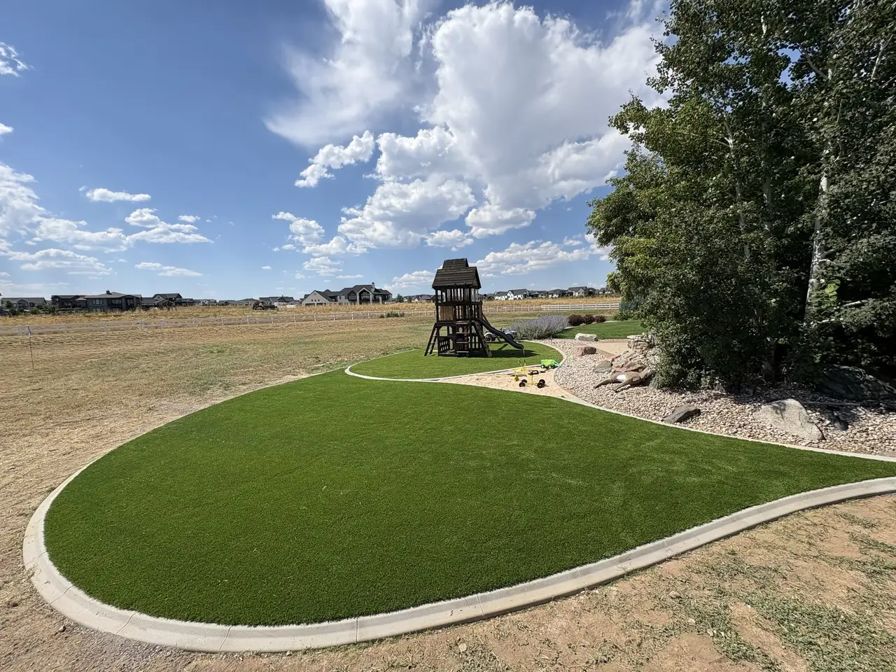 Artificial lawn and green with a wooden playset, open ground beyond