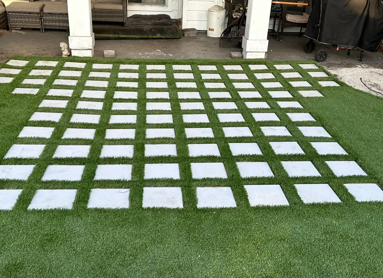 Artificial turf set in the joints between a grid of square concrete pavers