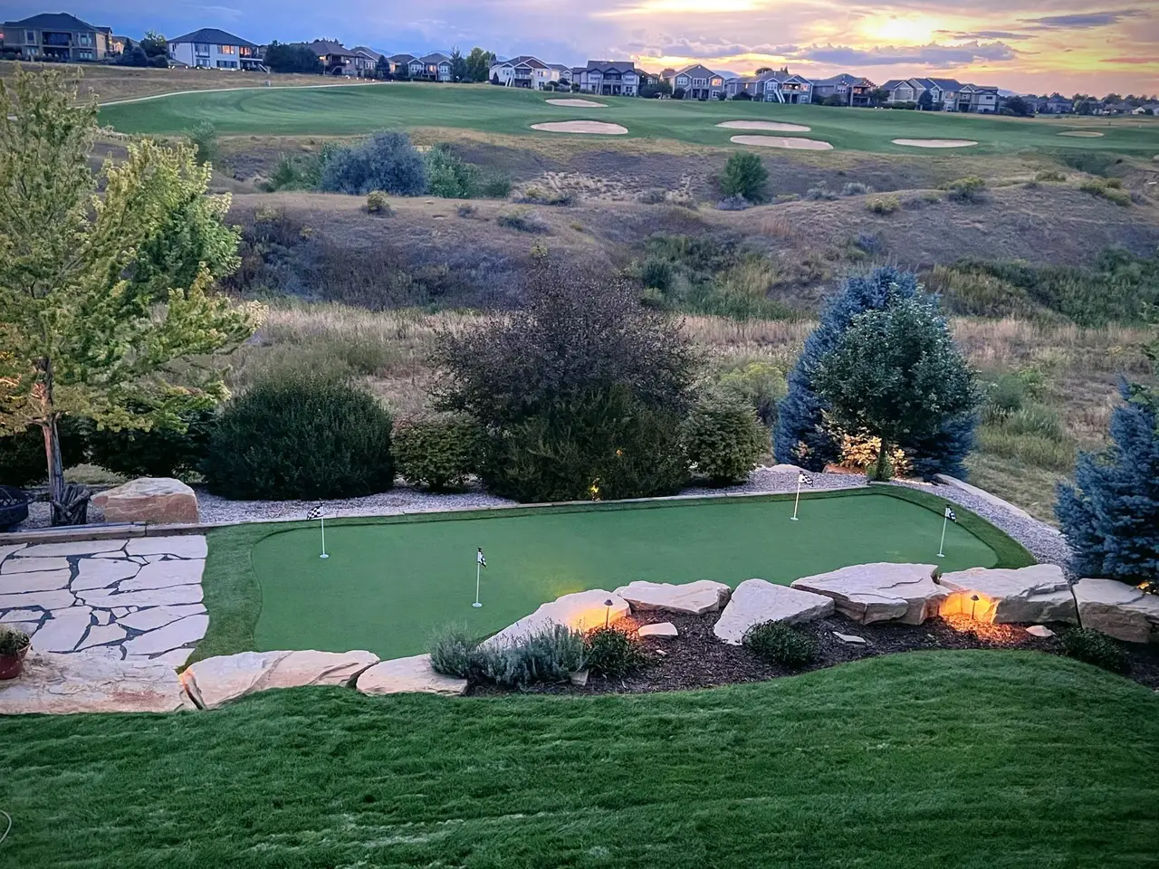A wide view of a backyard putting green at sunset