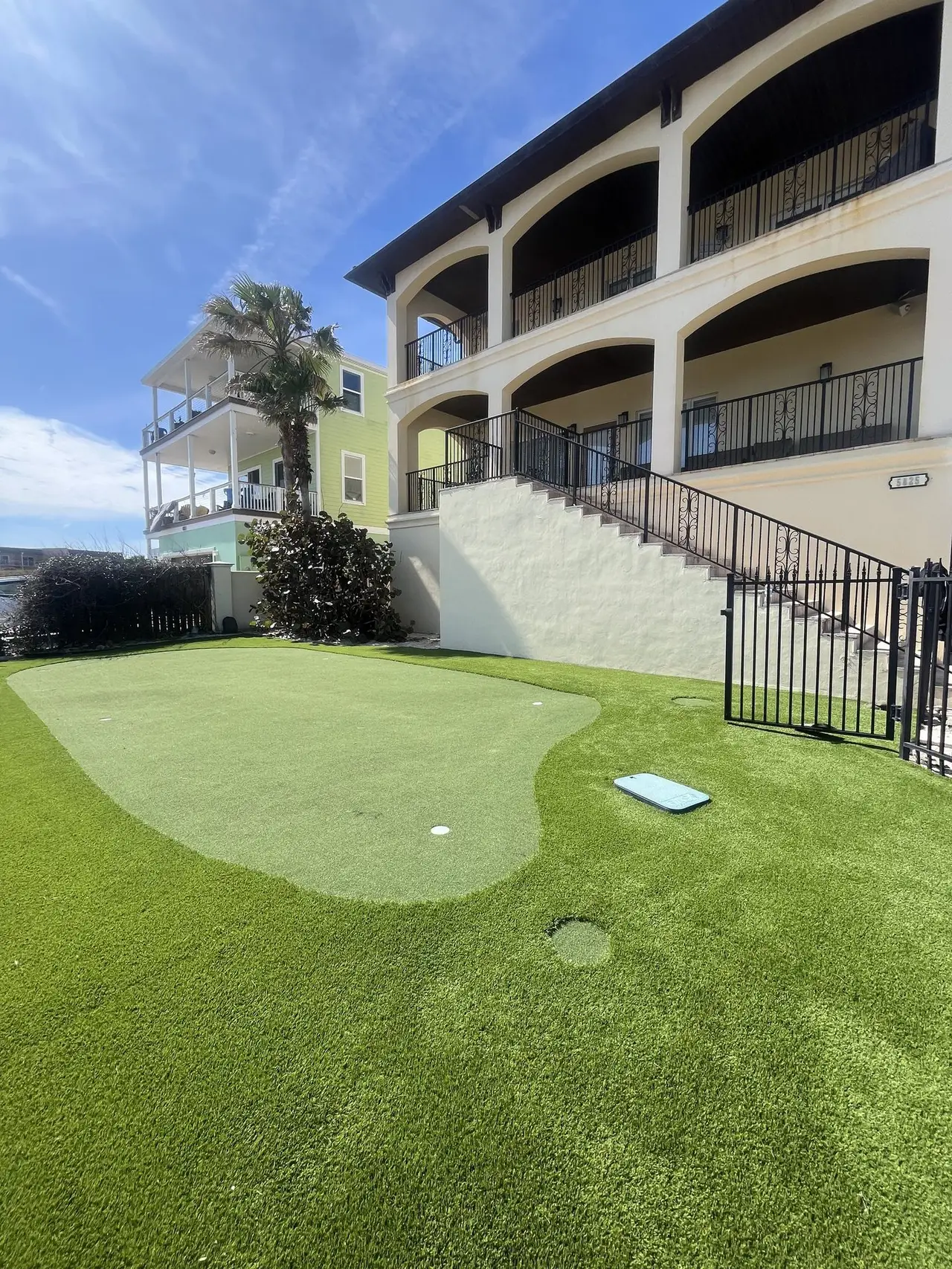 A putting green on a shared lawn beside a residential building